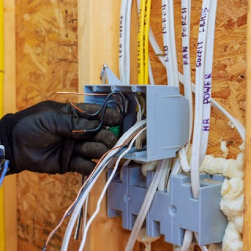 Electrician connects wires inside circuit box while renovating home, ensuring proper electrical setup